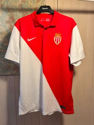 AS Monaco 2014/15 Nike shirt, size L - Good condition.  #falcao #moutinho #bernardosilva #fabinho #france #nike #ligue1 #asmonaco  Röd och vit AS Monaco FC fotbollströja med klubbmärket och Nike-loggan på bröstet. Tröjan har en klassisk polokrage och korta ärmar.