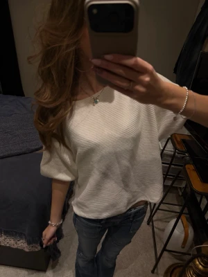 Vit ribbad t-shirt med kort ärm Kappahl  - Säljer en vit t-shirt med diskreta ribbade ränder. Modellen är loose fit med korta ärmar och rund hals. Perfekt för en chill och avslappnad stil. Materialet känns mjukt och skönt mot huden.