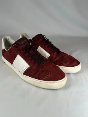 Valentino Rockrunner vinröda sneakers - Snygga Valentino Rockrunner sneakers i vinrött mocka och vitt skinn. Skorna har svarta snören, vita detaljer på sidan och hälen samt coola nitar längs sidan! Storlek 44. Nypris ca - 7000 kr. 