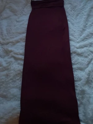 Mörkröd långkjol i enkel design - Säljer en stilren mörkröd långkjol med rak passform. Kjolen har en minimalistisk look utan mönster eller detaljer och är perfekt för dig som gillar en clean och elegant stil. Materialet känns mjukt.