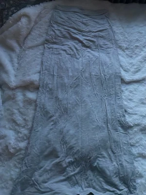 Ljusgrå långkjol i mjukt tyg - Enkel och stilren ljusgrå långkjol i mjukt och tunt material. Kjolen har rak passform och resår i midjan för extra komfort. Perfekt att styla med en crop top eller hoodie för en chill look. Den är skrynklig för den har varit vikt länge i min garderob 