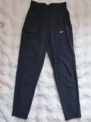 Svarta luftiga träningsbyxor  - Högmigjade svarta träningsbyxor som går att vika ner vid behov. Dem har ett väldigt luftig och tunntarmen och skänt material som är stretchingt, från Nike.