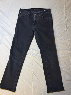 Nudie jeans svarta – Slim fit – 28/28 – Mycket snygga - Säljer ett par svarta Nudie jeans, slim fit, storlek 28/28, i mycket snyggt skick. Kortare längd gör dem perfekta för cropped look eller low-stack fit.  Klassisk svart denim som funkar till allt – från streetwear till clean outfits.  Mått: Midja: 37 cm Längd: 86 cm  • Märke: Nudie Jeans • Passform: Slim • Färg: Svart  Nudie 3