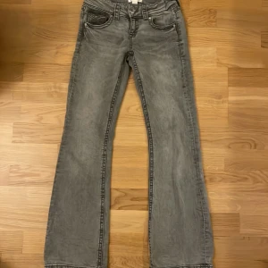 Grå bootcut jeans med fickdetaljer - Säljer ett par grå jeans med bootcut-modell och snygga fickdetaljer med knappar både fram och baksida. Är från Gina tricot