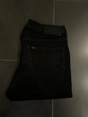 Svarta Lee Daren Zip Fly jeans W29 L32 - Säljer ett par svarta Lee Daren Zip Fly jeans i storlek W29 L32. Klassisk femficksmodell med dragkedjegylf och Lee-logga på bakfickan. Jeansen har en rak passform och är tillverkade i mjukt jeansmaterial.