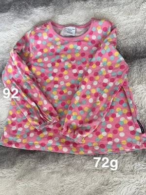 Rosa prickig tröja Polarn O. Pyret - Söt långärmad tröja från Polarn O. Pyret i rosa med färgglada prickar i vitt, gult, blått och cerise. har rund halsringning samt resår vid ärmsluten. Perfekt för lek och vardag!🌸 Fint använt skick.Storlek 92