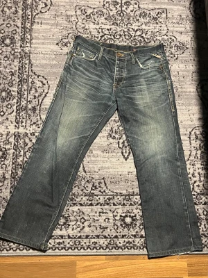 Blå jeans från Jack & Jones vintage -  Ett par snygga blå jeans från Jack & Jones straight passform och klassisk femficksdesign. Båda fickorna hade hål men är fixade och har inte upplevt något problem sen dess. Jeansen har slitningar och kontrastsömmar, eleganta färgstänk samt detaljerade bakfickor med broderade linjer. Materialet är robust denim och färgen är mörkblå med ljusare tvättade partier. Perfekta jeansen som passar till allt🤩🤩