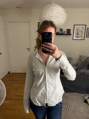 Marc O’Polo Skjorta - Superfin långärmad skjorta från kvalitetsmärket Marc O’Polo i storlek 40. Skjortan är vit med klassiska svarta prickar (polka dots) och har vackra blommiga detaljer på insidan av kragen. En tidlös garderobsklassiker som passar lika bra på kontoret som till en mer dressad vardagslook. Skönt material med hög kvalitet. • Märke: Marc O’Polo • Storlek: 40 • Skick: Mycket gott skick • Nypris: Ca 800–1 000 kr.