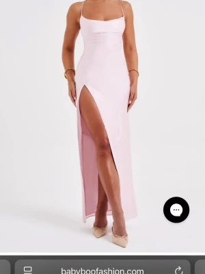 Ljusrosa långklänning med slits - Supersnygg ljusrosa långklänning från Babyboo med tunna axelband, öppen rygg med snörning och hög slits på sidan. Klänningen har en figurnära passform och är gjord i ett glansigt satinliknande material som ger en lyxig känsla. Använd 1 gång!