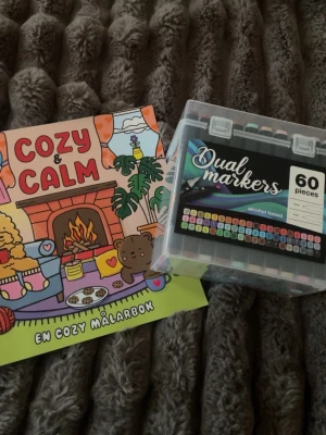 Virala pennor & målarbok ”cozy”  - 📚Cozy & calm målarbok: 6 av 25 sidor är använda. Nypris 129kr, från Lekia.  - Den gröna sidan är till för att skydda nästa sida man målar, från att bli förstörd. Den är använd som man kan se   🎨Dual markers: 60st dubbelsidiga pennor. Nypris 200kr, från Rusta   
