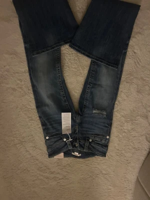 Blå low rise flare jeans XS Gina Tricot - Säljer ett par blå low rise flare jeans från Gina Tricot i storlek XS. Jeansen har snygga slitningar framtill, kontrastsömmar och broderade bakfickor. Klassisk femficksmodell med knapp och dragkedja. Perfekta för dig som gillar retrovibbar och utsvängda ben. Vet inte varför bilderna blev upp och ned på😅😅