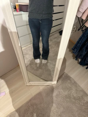 Mörkblå bootcut jeans med broderi - Säljer ett par mörkblå jeans med snygg bootcut passform och kontrastsömmar från gina young. Bakfickorna har detaljerat broderi i beige som ger extra stilpoäng. Jeansen har normal midja och är tillverkade i klassiskt jeansmaterial. Perfekta till sneakers eller boots! Sömmen har lossnat lite som man kan se på sista bilden, men inget som syns super mycket 