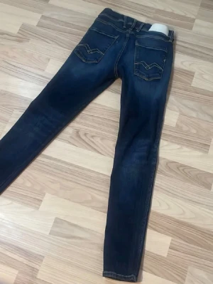 Replay Anbass slim fit jeans blå - Säljer ett par mörkblå Replay Anbass jeans i slim fit med klassiska fem fickor och snygga kontrastsömmar. Jeansen har låg midja och smal passform som sitter tajt längs benen. Materialet är stretchigt jeans för extra komfort.