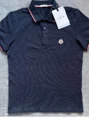 Blå Moncler piké t-shirt - Säljer en äkta mörk blå moncler piké. Mycket bra skick. Säljs pga av att bara rensa garderoben lite. Storlek S. Finns kvitto. Hör av vid intresse!!☺️