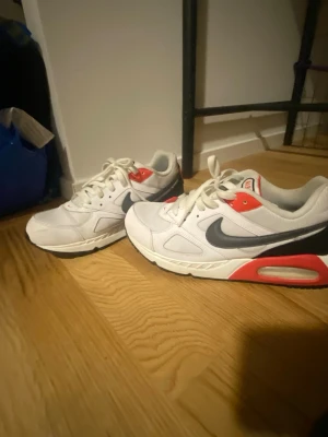 Nike Air Max IVO (CD1540-100) skor - Säljer ett par Nike Air Max IVO i vitt/svart/rött. Bra begagnat skick, hela och rena. Storlek: 43 Pris: 350 kr, diskuterbart vid snabb affär.