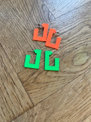 Två par statementörhängen  -  Sälja två par statement örhängen i geometriskaformer i grönt och orange. Perfekt för dig som älskar statement  accessoarer 