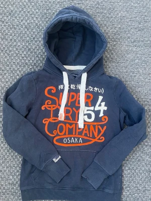 Vintage 2000s Superdry hoodie (Sällsynt) - Säljer nu denna sjukt snygga vintage 2000s hoodie från Superdry i nästintill nytt skick och perfekt passform🙌 Storlek M och passar true to size🤝 Både varm och bekväm så passar perfekt till vintern och våren😊 Säljs ej längre i butik och är därav mycket eftertraktad 🤩 Skriv vid funderingar 📲