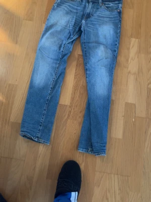 Levi's 511 blå jeans W30 L32 - Säljer ett par klassiska Levi's 511 jeans i blå tvätt. Modellen har en slim passform med raka ben och fem fickor. Jeansen är tillverkade i slitstarkt denim och har den ikoniska läderpatchen bak i midjan. Perfekta till vardagslooken.