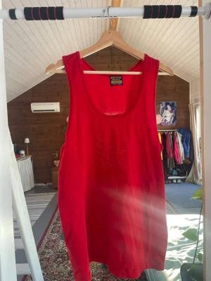 Rött linne - Snygg röd linnetopp från Maska med rundad halsringning och ärmlös design. Tillverkad i ett lätt och luftigt material. Enkel och stilren modell som är lätt att matcha. Ingen lapp men skulle säga L, den är stretchig.