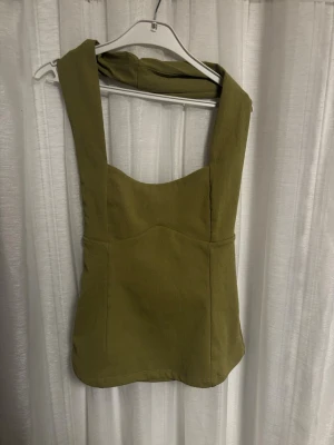 Halterneck top från Zara - Snygg olivgrön halterneck top från Zara med breda axelband och markerad byst. Toppen har en figurnära passform och är i storlek S. 💚✨
