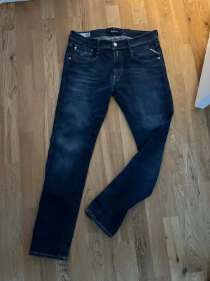 Replay mörkblå jeans  - Säljer ett par snygga mörkblå jeans från Replay med klassisk femficksdesign och ljusa sömmar. Jeansen har raka ben och diskreta slitningar framtill och bak, samt Replay-logga på insidan. Perfekt för dig som gillar stilrena och tidlösa jeans.