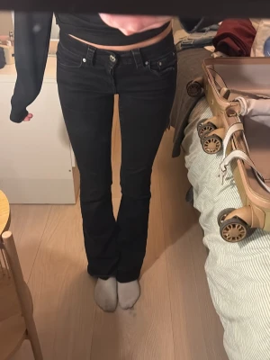 Svarta jeans gina  - Säljer ett par svarta jeans med bootcut passform och snygga silverknappar på bakfickorna från gina  