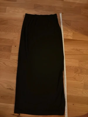 Svart långkjol från SHEIN, stl S - Enkel svart långkjol från SHEIN i storlek S. Kjolen är rak i modellen och har resår i midjan för skön passform. Längden är ca 93 cm. Perfekt till sneakers eller boots för en clean look. Det finns ett litet hål i kanten men syns inte när man har på sig den, går säkert att laga 