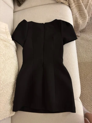 VIRALA zara klänning  - Säljer en svart kortklänning med enkel och stilren design. Klänningen har korta ärmar, markerad midja och diskreta sömdetaljer framtill. Materialet känns slätt och något stadigt, perfekt för dig som gillar minimalistisk och chic stil. Liten skada som man ser på 2 bilden men inget man tänker på.