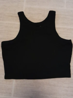 Svart croppad linnetopp  - Säljer en svart croppad linnetopp från 157. Toppen har en enkel och stilren design med breda axelband och hög halsringning. Perfekt att matcha med höga jeans eller kjol för en clean look. !!endast swish +frakt!!