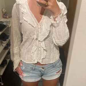 Vit blus med volang från Zara XS - Supersöt vit blus från Zara i storlek XS med v-ringning, volangdetaljer och spets längs bröstet. Inga fläckar eller hål ❤️men lite krymt i tvätten så den är mindre i storlek