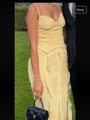 Oh Polly Ljusgul långklänning med smala axelband - Supersnygg ljusgul långklänning med smala axelband och figurnära passform. Klänningen har en djup urringning och vågiga detaljer längs kjolen som ger en unik look. Perfekt för dig som vill sticka ut med en feminin och elegant stil. Klänningen är i storlek 6/XS och är använd endast en gång så den är i mycket bra skick💛