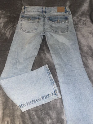 Ljusblå bootcut jeans från Gina tricot  - Säljer ett par ljusblå bootcut jeans från Gina tricot i storlek 38. De har klassiska fem fickor, snygga ficklock med knapp bak och normal passform. Jeansen är i mjukt denimtyg och har en riktigt fräsch tvättad look. Perfekta till sneakers eller boots.