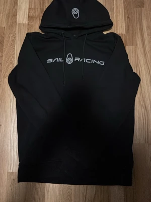 Skal Racing Hoodie - Svart Sail Racing hoodie. Gjort av skönt material som man knappt vill ta av sig.Har tyvärr växt ur den och är därför jag säljer vidare den.