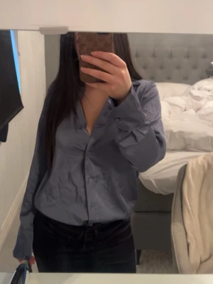 Blå långärmad skjorta med knappar - Säljer en blå satin skjorta med knappar, använt fåtal gånger