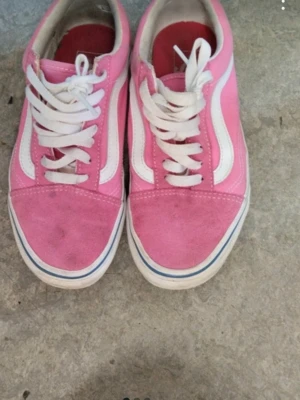 Rosa och vita Vans sneakers - Säljer ett par klassiska Vans sneakers i rosa och vitt med vit sula och den ikoniska vågformen på sidan. Skorna har snörning och ovandel i mocka och textil. Perfekta för dig som vill ha en färgklick till din outfit!