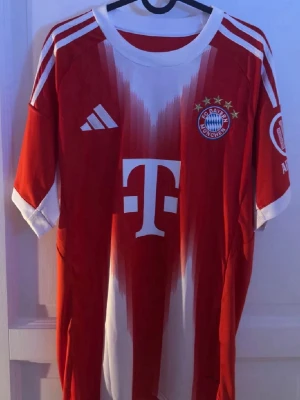 Bayern München Adidas matchtröja L - Säljer en röd och vit Bayern München matchtröja från Adidas i storlek L. Tröjan har klubbmärke och Adidas-logga på bröstet, samt vita detaljer och ränder på axlarna. Tillverkad i polyester och har slim fit passform.