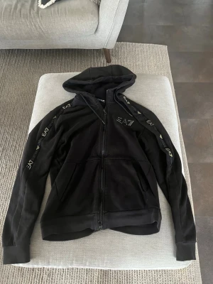 Svart ea7 tröja med guldiga detaljer  - Svart skön hoodie,med guld detaljer på ea7 märkte på bröstet och på armarna 