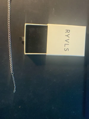 Silvrigt kedjearmband från RYVLS - Säljer ett stilrent armband från RYVLS i silverfärgad metall. Kedjan har en klassisk, enkel design som passar till många olika looks. Låset är smidigt och armbandet kommer i originalask. Perfekt accessoar för dig som gillar minimalistisk stil.