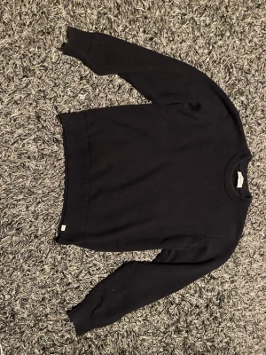 Marinblå stickad tröja från Les Deux - Klassisk marinblå stickad tröja från Les Deux med rund halsringning och ribbade muddar. Enkel och stilren design som funkar till allt. Perfekt för dig som gillar en clean look och vill ha något bekvämt och snyggt. Ser rätt så mörk ut på bild men är blåare irl 