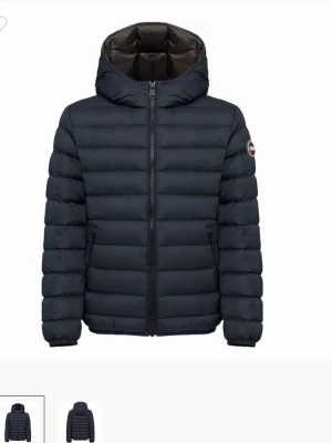 Mörkblå dunjacka från Colmar - Säljer en mörkblå dunjacka från Colmar med huva och hel dragkedja framtill. Jackan har quiltad design, två sidofickor med dragkedja och en rund logotyp på ärmen. Perfekt för kyliga dagar och riktigt snygg till streetwear. Använd en gång. Skickar fort!!!