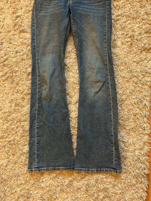 Blå bootcut jeans med dubbla knappar ginatricot  - Säljer ett par klassiska blå bootcut jeans med dubbla knappar i midjan och femficksmodell. Jeansen har en snygg tvättad look och är tillverkade i slitstarkt denimtyg. Passformen är normal och benen har en lätt utsvängd siluett. Dom är i storlek 158 men passar även 164💓😇😇