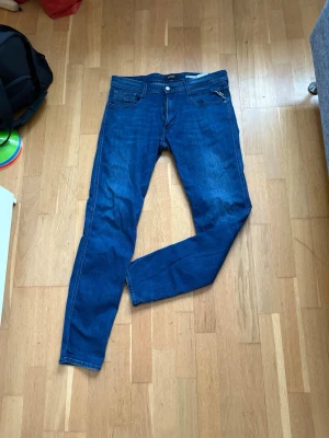 Replay Anbass blå jeans herr - Säljer ett par Replay Anbass jeans i klassisk blå tvätt. Modellen har smal passform med normal midja och raka ben. Jeansen har fem fickor, Replay-logga på bakfickan och snygga kontrastsömmar. Perfekta till sneakers eller boots.34/34