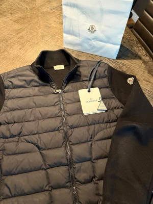 Moncler Cardigan  - Moncler Cardigan! Efter 3 år säljer ja nu men otroligt snygga moncler cardigan. Det är storlek M och har helt enkelt blivit för liten nu. Den e sparsamt använd men som ni kan tänka er efter 3 år har den slitits lite. Personen på bilden är 195 skulle säga 180-190 är en bra längd. Har kvitto men är på min pappas telefon då ja fick den i present så bara skriv om ni vill ha bild! Nypris: 11000kr
