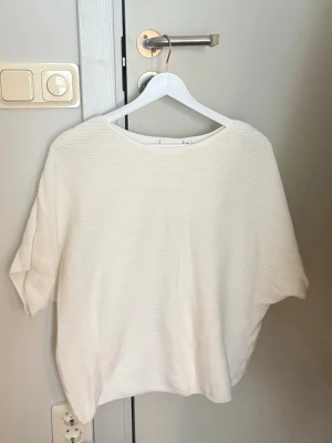 Vit ribbad topp med kort ärm - En enkel och stilren vit topp med ribbad struktur och korta ärmar från Kappahl.