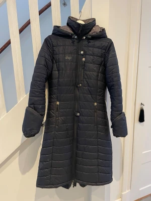 uhip kappa - Lång mörkblå kappa från uhip i storlek 36😊Dragkedjan har tyvärr gått sönder på ena fickan, men annars bra skick!