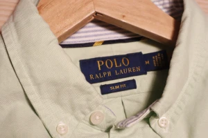 Ljusgrön skjorta från Polo Ralph Lauren M - Fräsch ljusgrön skjorta från Polo Ralph Lauren i slim fit. Klassisk button-down krage, broderad logga på bröstet och vita knappar framtill. Skjortan är långärmad och tillverkad i mjuk bomull, perfekt för en clean och chill stil.