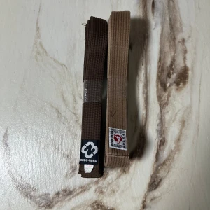 Brunt bälte från Budo-Nord 300cm - Säljer ett brunt kampsportsbälte från Budo-Nord, 300 cm långt. Bältet är tillverkat i en blandning av bomull och polyester och har klassisk design med broderad etikett. Perfekt för dig som tränar karate eller annan budosport.