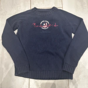 Mörkblå stickad tröja från Bondelid - Snygg mörkblå stickad tröja från Bondelid med broderad logga. Uppskattad storlek M