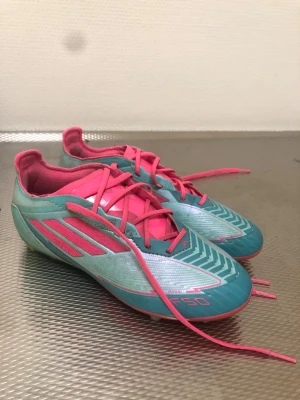 Adidas F50 Elite Messi - Blå Rosa Adidas F50 EliteMessi skor som är perfekt för dig att använda för träningar och matcher för att dem är sköna och är hållbara. Bara lite smutsig men annars inget fel med dem. Ny pris 1500kr Säljer för 450kr. Storlek Eu 36