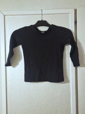 Svart långärmad topp från lager 157 - En basic svart långärmad topp från 157, tillverkad i 100% bomull. Modellen har rund halsringning och en rak passform som funkar till många olika stilar. Perfekt att matcha med jeans eller kjol.